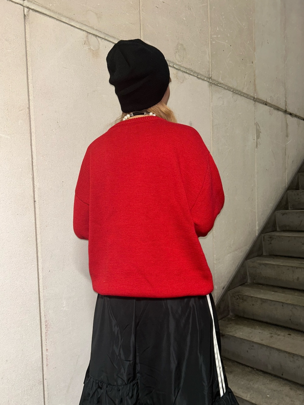 レッド系のニット/セーター、ブラック系のスカート、ブラック系のチョーカーを着用したレディースの秋コーディネートの6枚目の写真