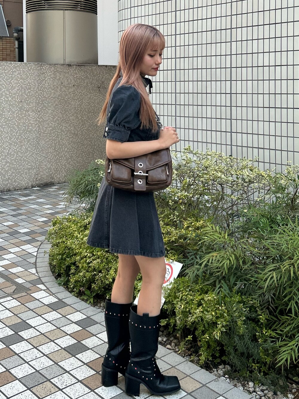 ブラック系のワンピース、ブラック系のブーツ、ブラウン系のハンドバッグを着用したレディースの春コーディネートの2枚目の写真