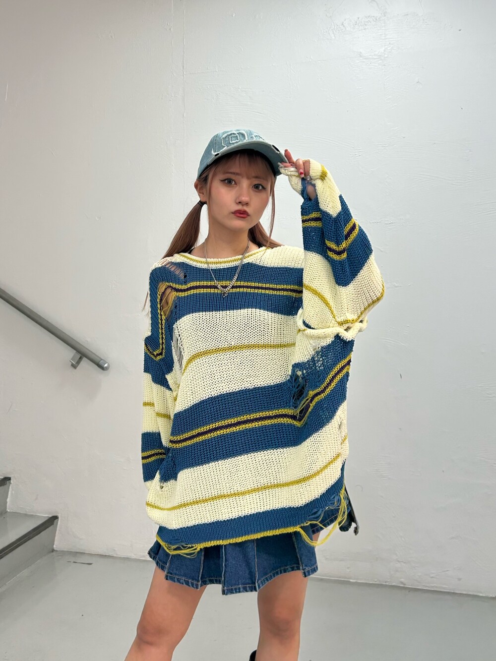 ホワイト系のニット/セーター、ブルー系のデニムスカート、ブラック系のブーツを着用したレディースの春コーディネートの4枚目の写真