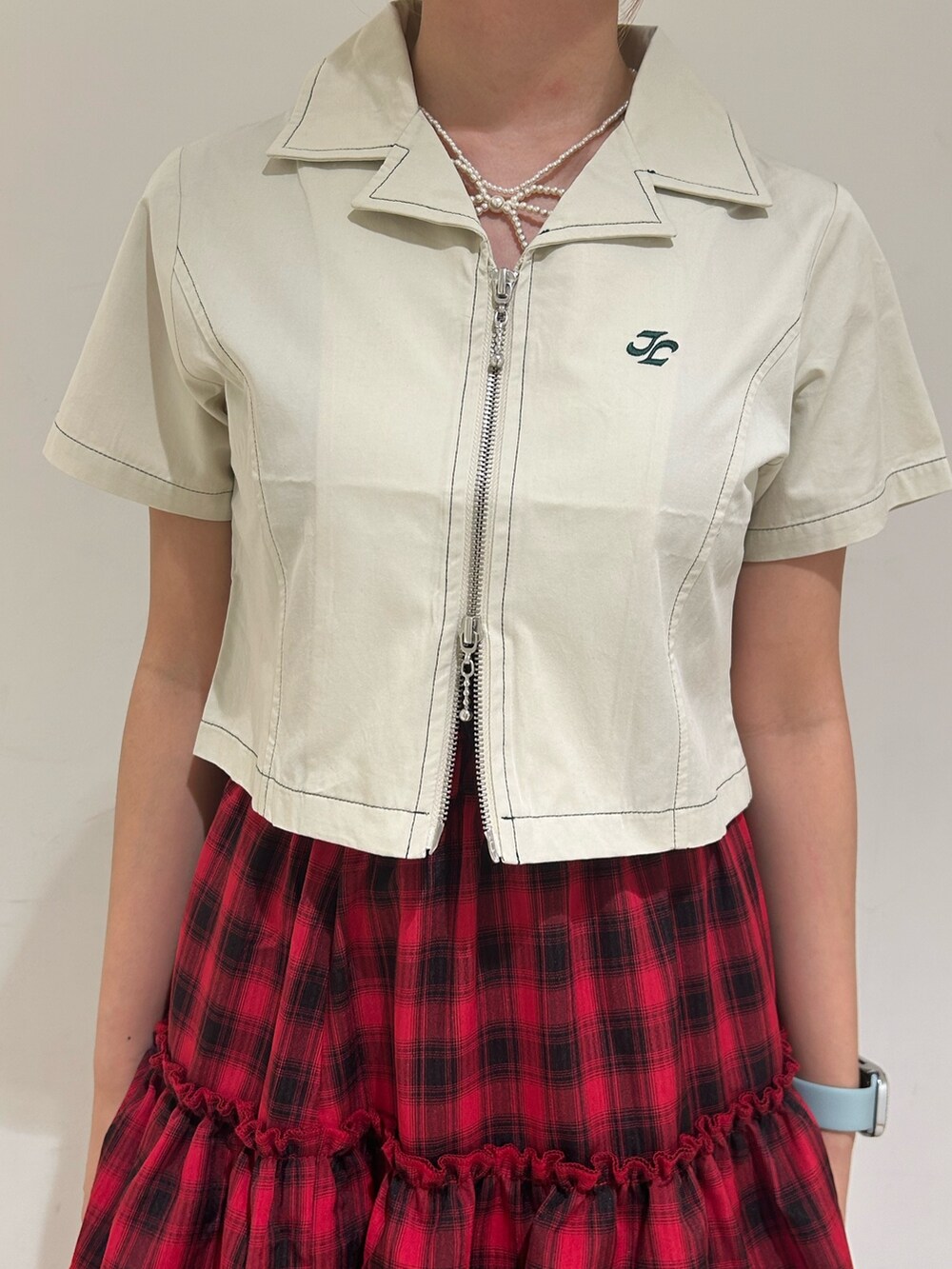 ホワイト系のシャツ/ブラウス、レッド系のスカート、ゴールド系のネックレスを着用したレディースの春コーディネートの6枚目の写真