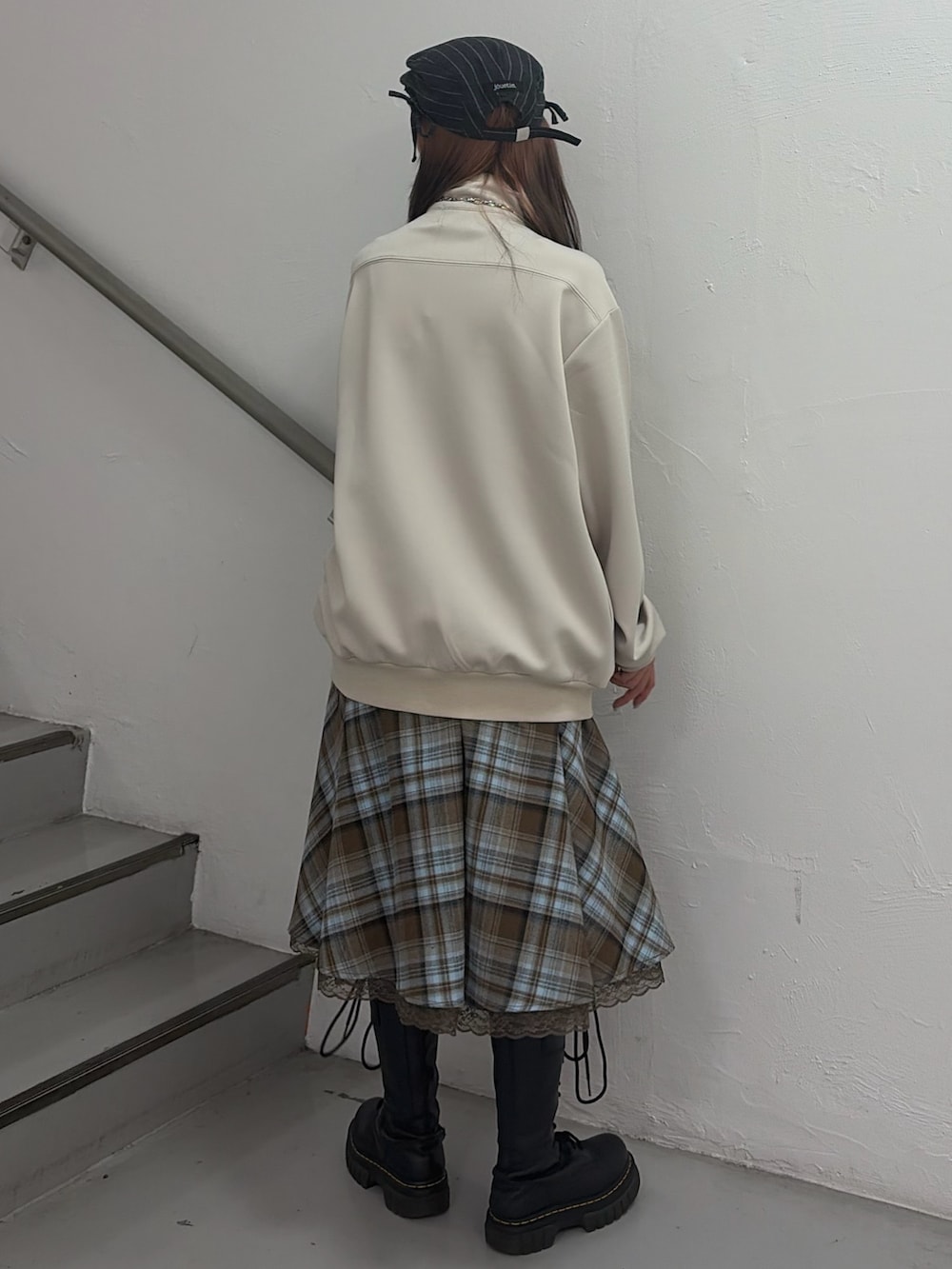 ホワイト系のジャージ、ブラウン系のスカート、グレー系のハンチング/ベレー帽を着用したレディースの冬コーディネートの3枚目の写真