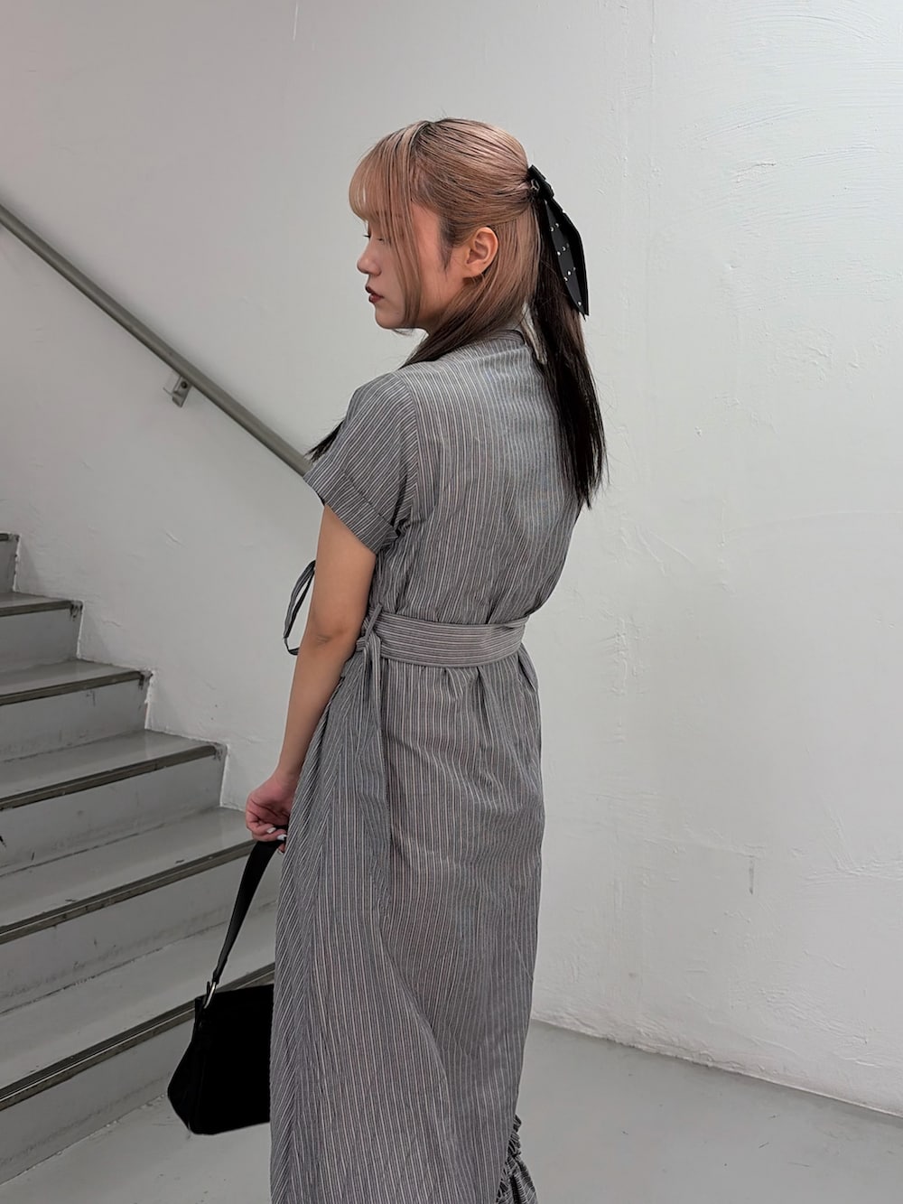 グレー系のワンピース、ブラック系のハンドバッグを着用したレディースの春コーディネートの6枚目の写真