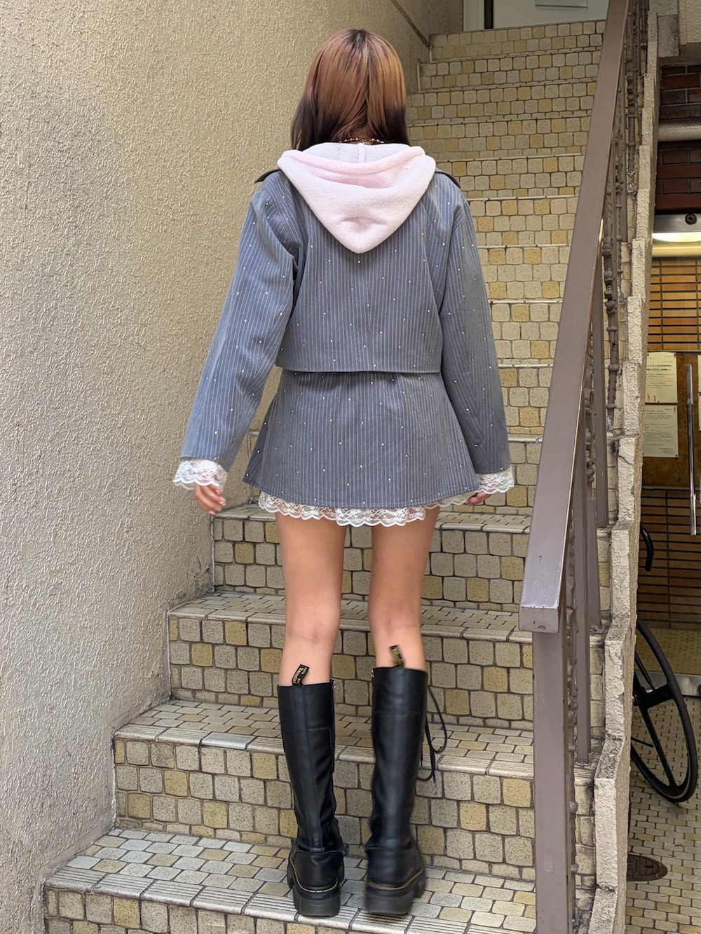 グレー系のテーラードジャケット、グレー系のスカート、ピンク系のパーカーを着用したレディースの冬コーディネートの3枚目の写真