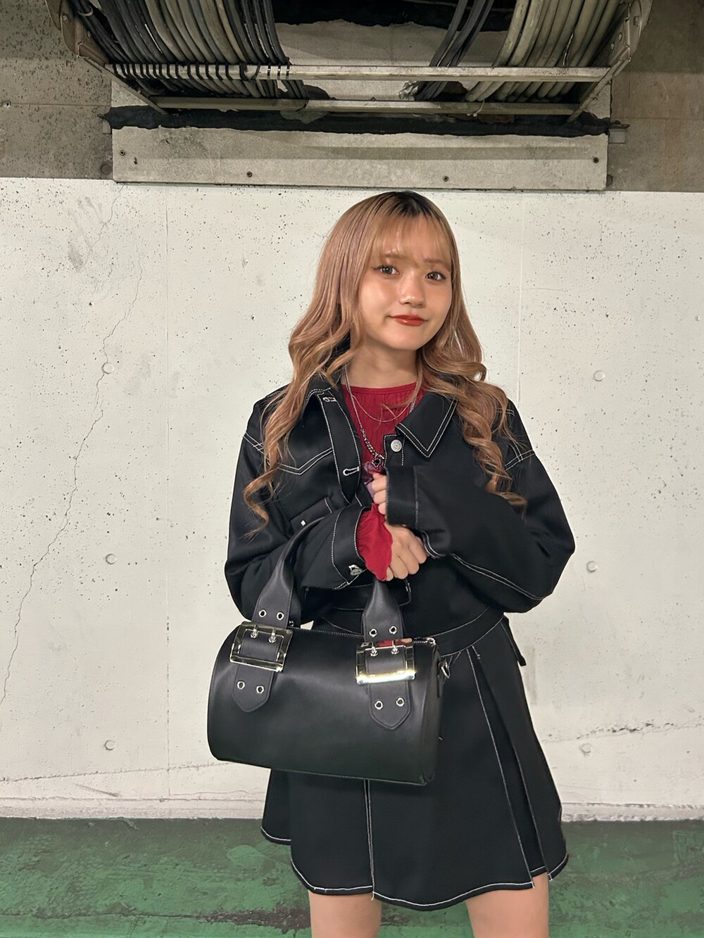 ブラック系のワンピース、レッド系のTシャツ/カットソー、ブラック系のボストンバッグを着用したレディースの春コーディネートの4枚目の写真