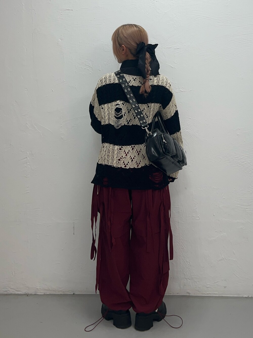 ブラック系のニット/セーター、ブラック系のボストンバッグ、レッド系のその他パンツを着用したレディースの冬コーディネートの3枚目の写真