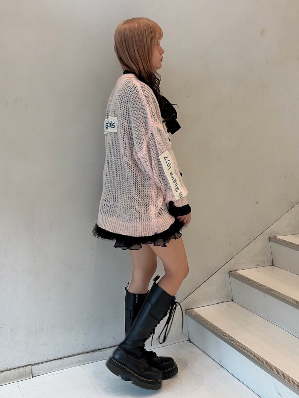 ピンク系のニット/セーター、ブラック系のスカート、ブラック系のシャツ/ブラウスを着用したレディースの秋コーディネートの3枚目の写真