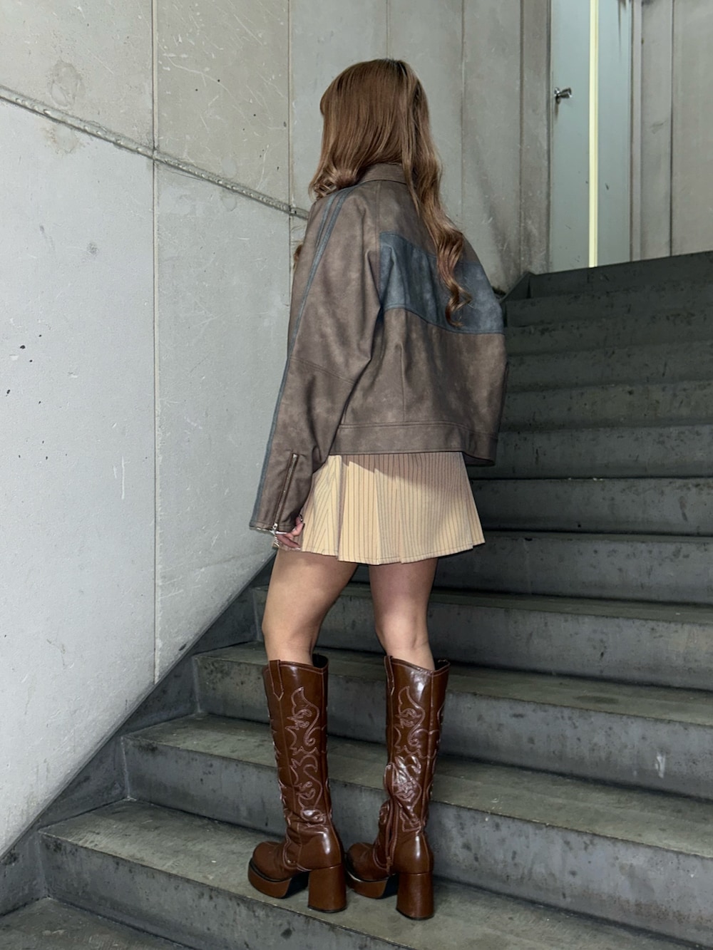 ブラウン系のブルゾン、ホワイト系のTシャツ/カットソー、ベージュ系のスカートを着用したレディースの冬コーディネートの3枚目の写真