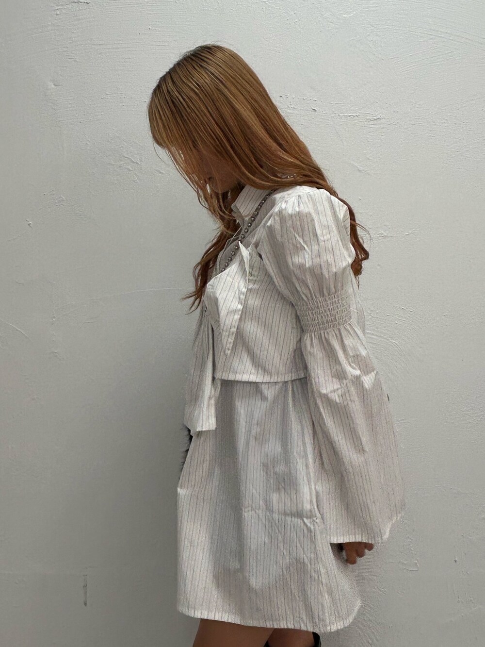 ホワイト系のシャツワンピース、ブラック系のハンドバッグ、ブラック系のブーツを着用したレディースの夏コーディネートの5枚目の写真