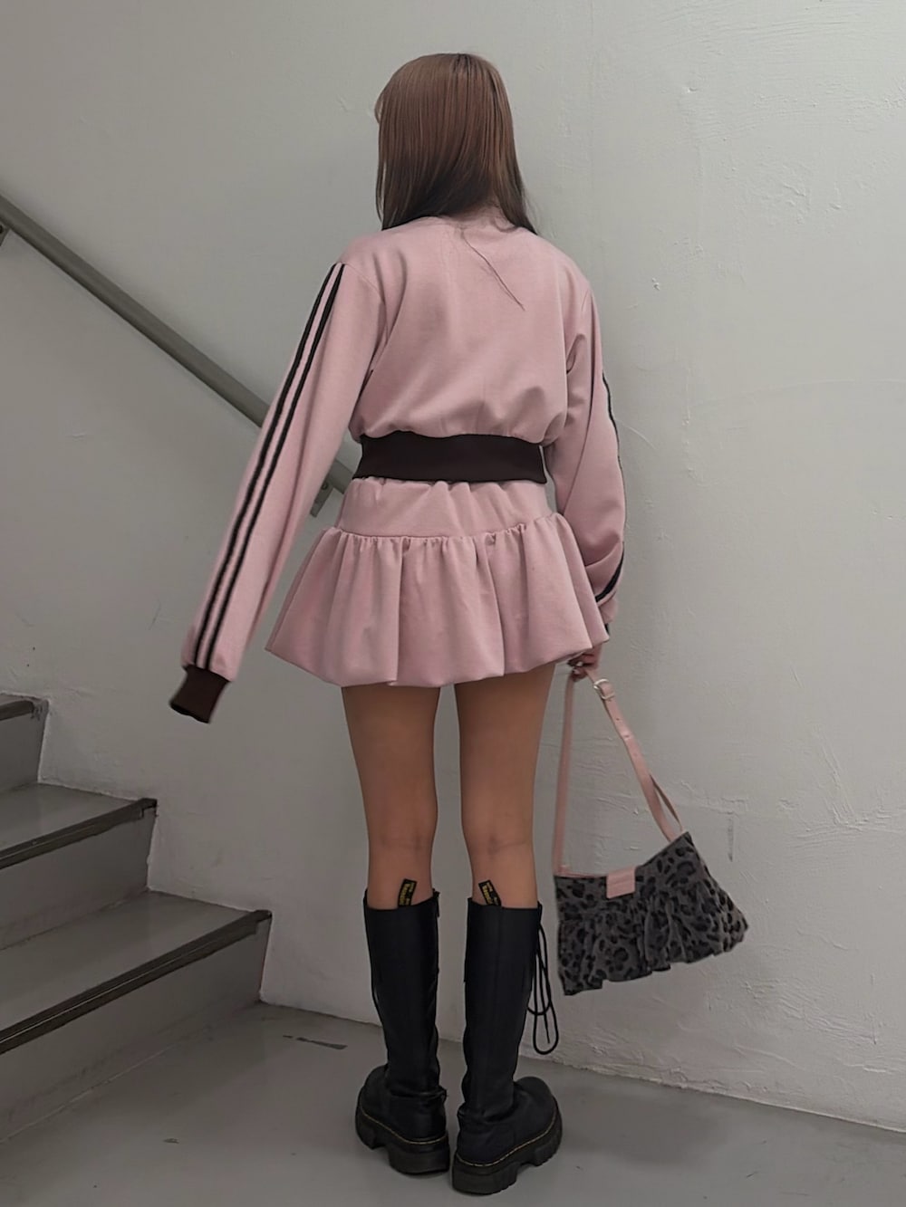 ピンク系のジャージ、ピンク系のスカート、ブラック系のハンドバッグを着用したレディースの冬コーディネートの4枚目の写真