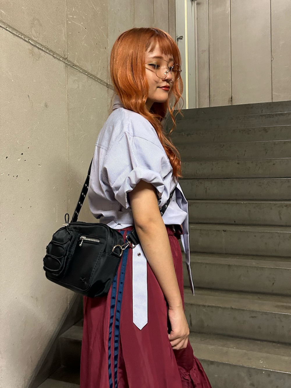 パープル系のシャツ/ブラウス、レッド系のスカート、ブラック系のショルダーバッグを着用したレディースの夏コーディネートの5枚目の写真