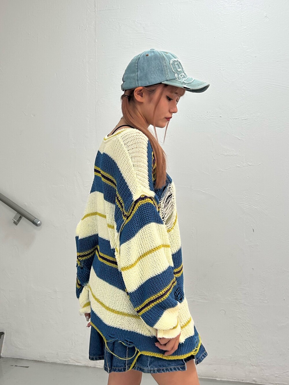 ホワイト系のニット/セーター、ブルー系のデニムスカート、ブラック系のブーツを着用したレディースの春コーディネートの5枚目の写真