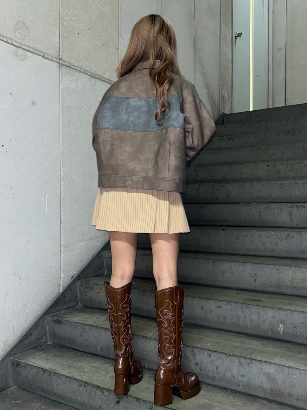 ブラウン系のブルゾン、ホワイト系のTシャツ/カットソー、ベージュ系のスカートを着用したレディースの冬コーディネートの2枚目の写真