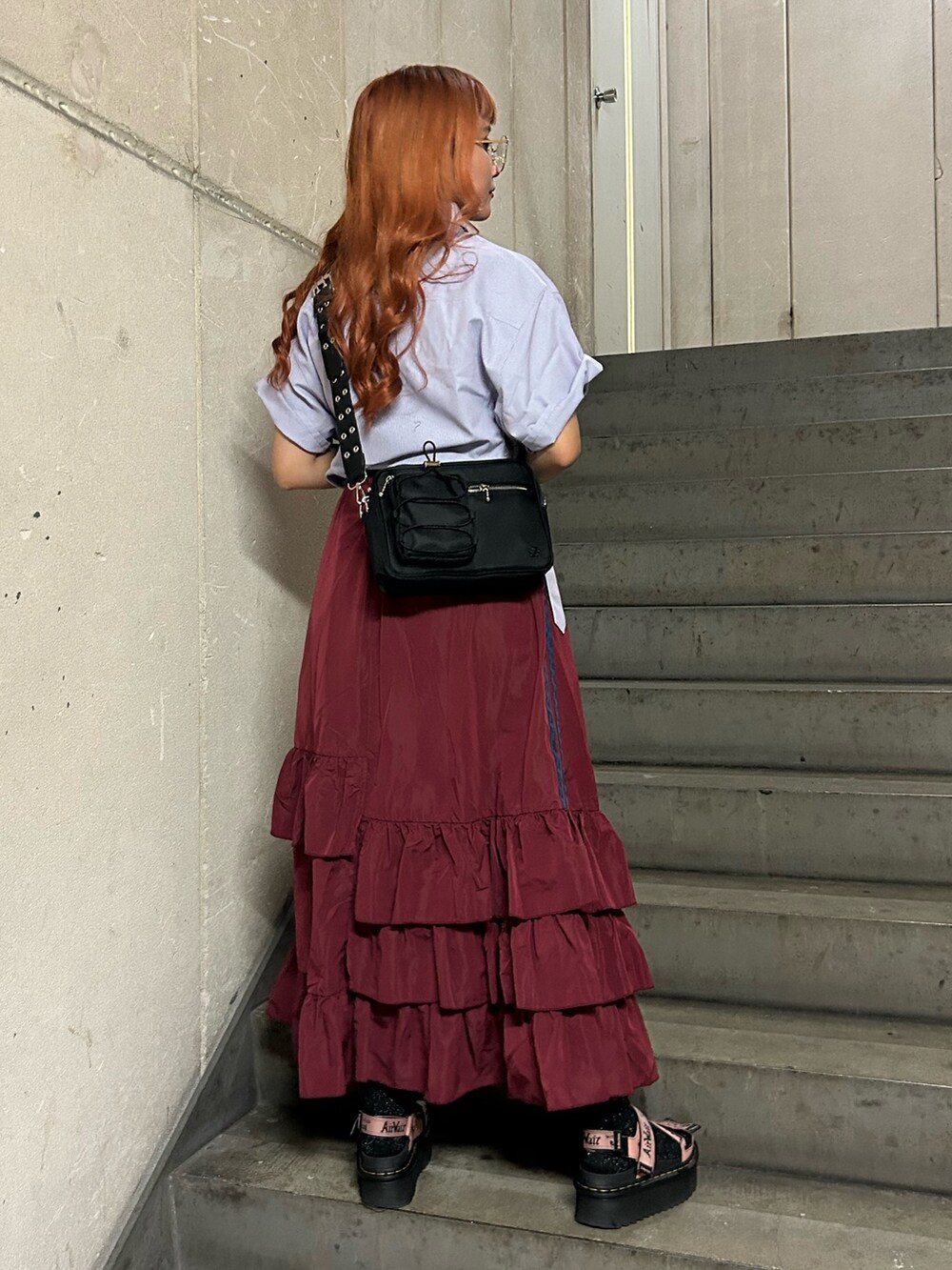 パープル系のシャツ/ブラウス、レッド系のスカート、ブラック系のショルダーバッグを着用したレディースの夏コーディネートの3枚目の写真