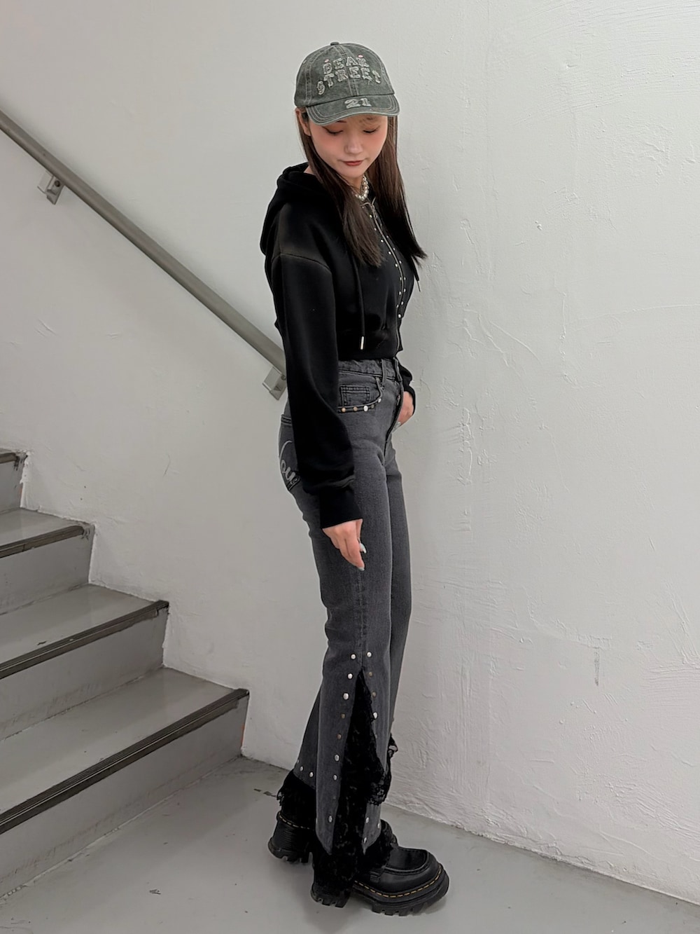 ブラック系のパーカー、ブラック系のデニムパンツ、ベージュ系のキャップを着用したレディースの春コーディネートの2枚目の写真