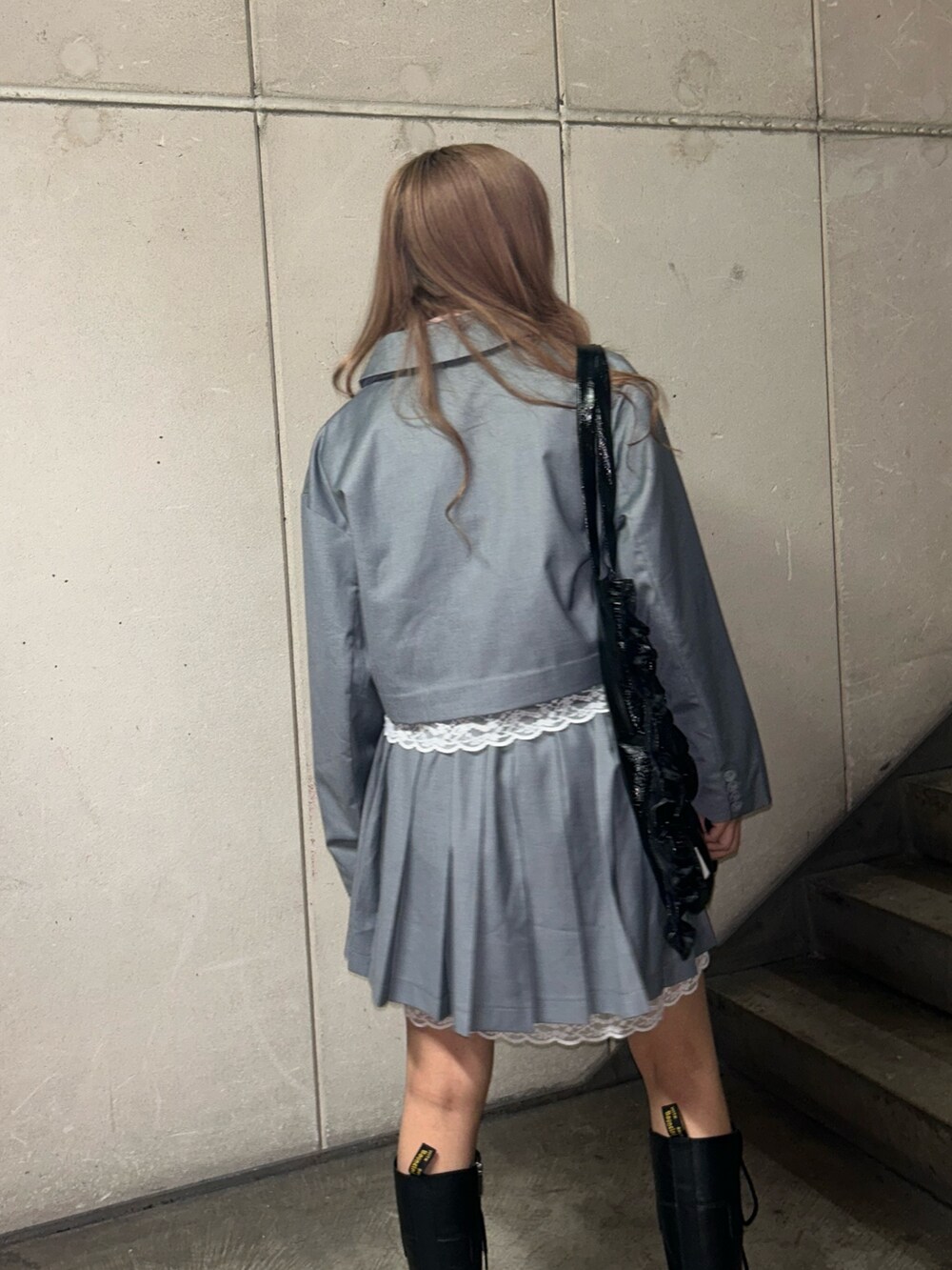 ブラック系のトートバッグ、グレー系のテーラードジャケット、グレー系のスカートを着用したレディースの冬コーディネートの6枚目の写真