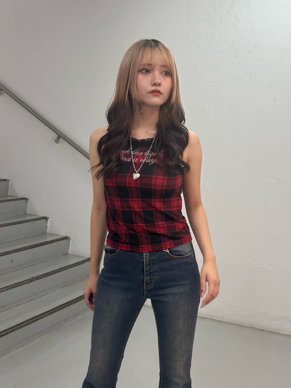 レッド系のタンクトップ、ブルー系のデニムパンツ、シルバー系のネックレスを着用したレディースの夏コーディネートの4枚目の写真