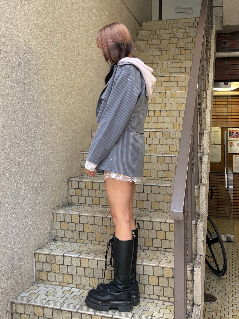 グレー系のテーラードジャケット、グレー系のスカート、ピンク系のパーカーを着用したレディースの冬コーディネートの2枚目の写真