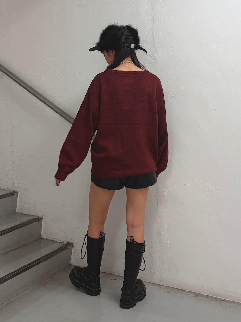 レッド系のニット/セーター、ブラック系のその他パンツ、ブラック系のキャップを着用したレディースの秋コーディネートの2枚目の写真