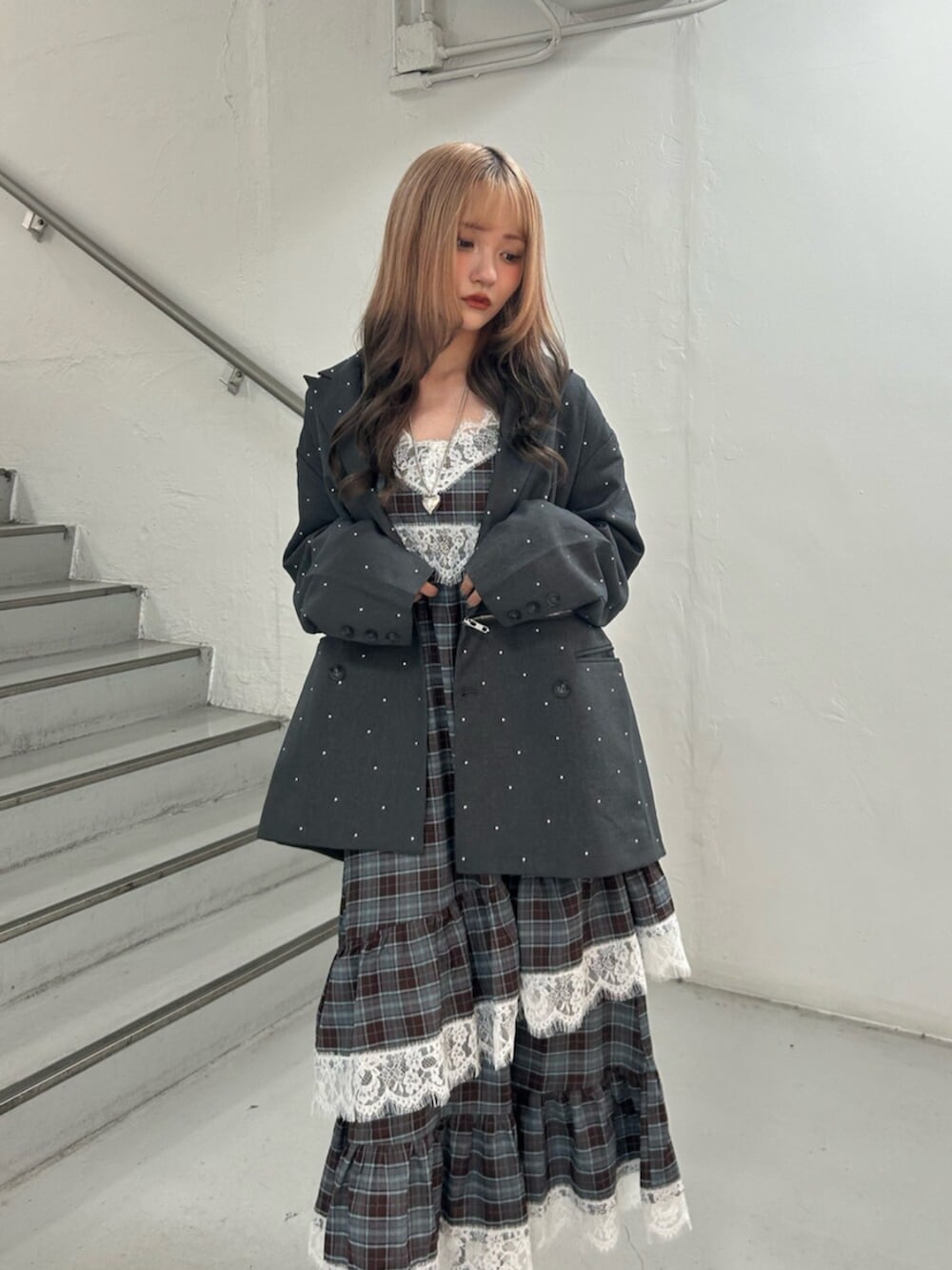 グレー系のテーラードジャケット、ブラック系のスニーカー、ブラウン系のワンピースを着用したレディースの秋コーディネートの4枚目の写真