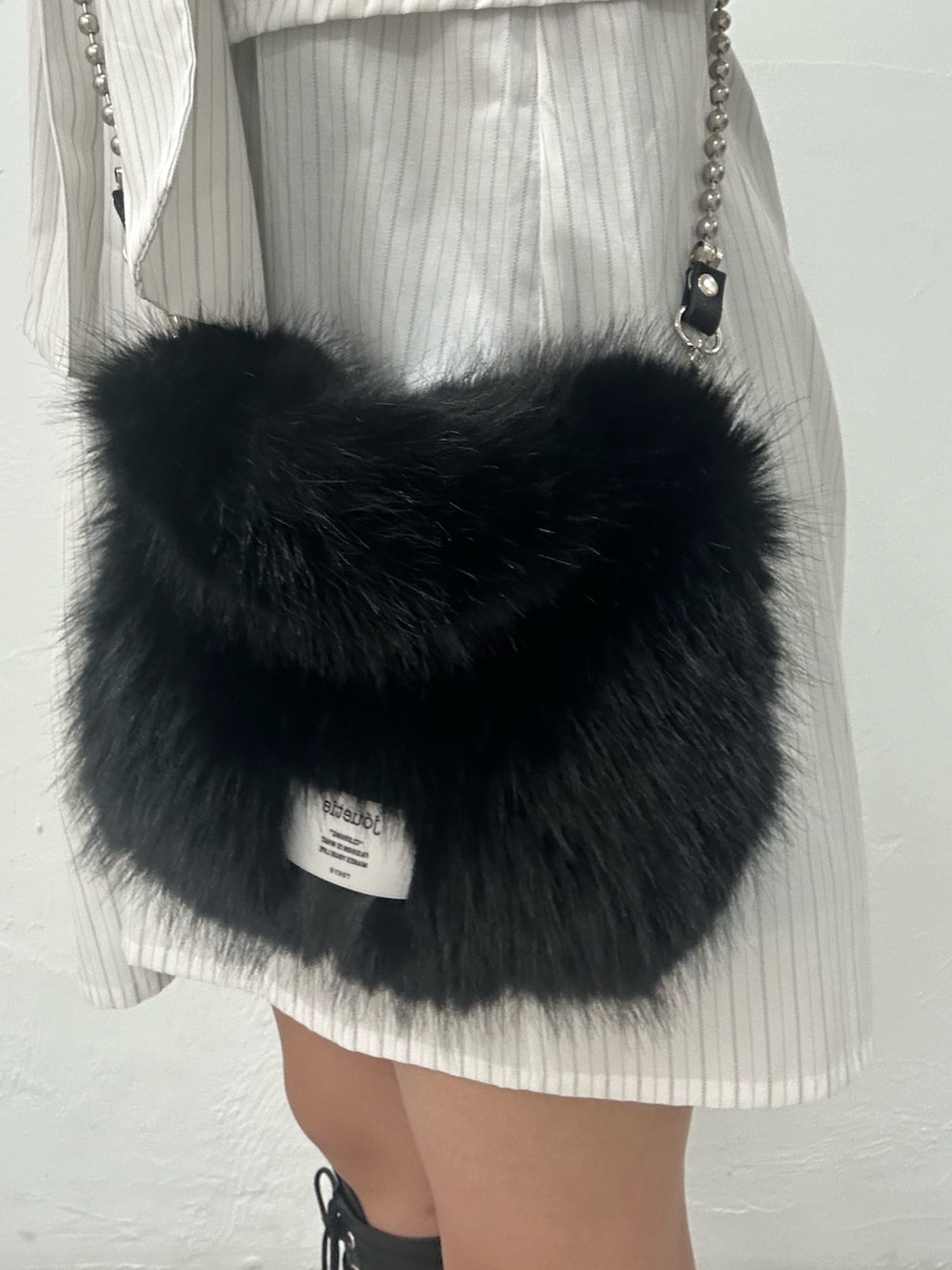 ホワイト系のシャツワンピース、ブラック系のハンドバッグ、ブラック系のブーツを着用したレディースの夏コーディネートの7枚目の写真