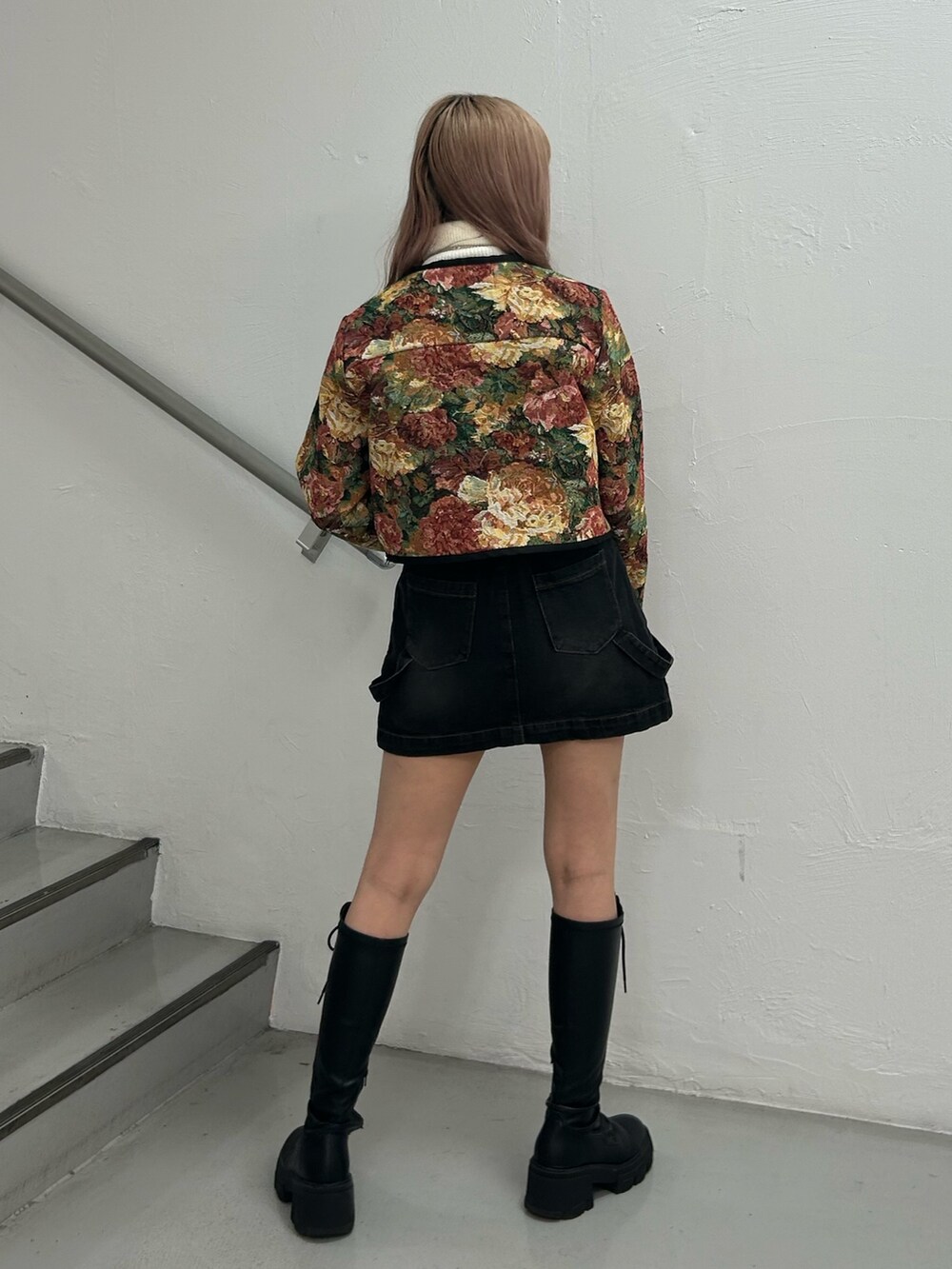 ブラック系のノーカラージャケット、ホワイト系のニット/セーター、ブラック系のデニムスカートを着用したレディースの冬コーディネートの3枚目の写真