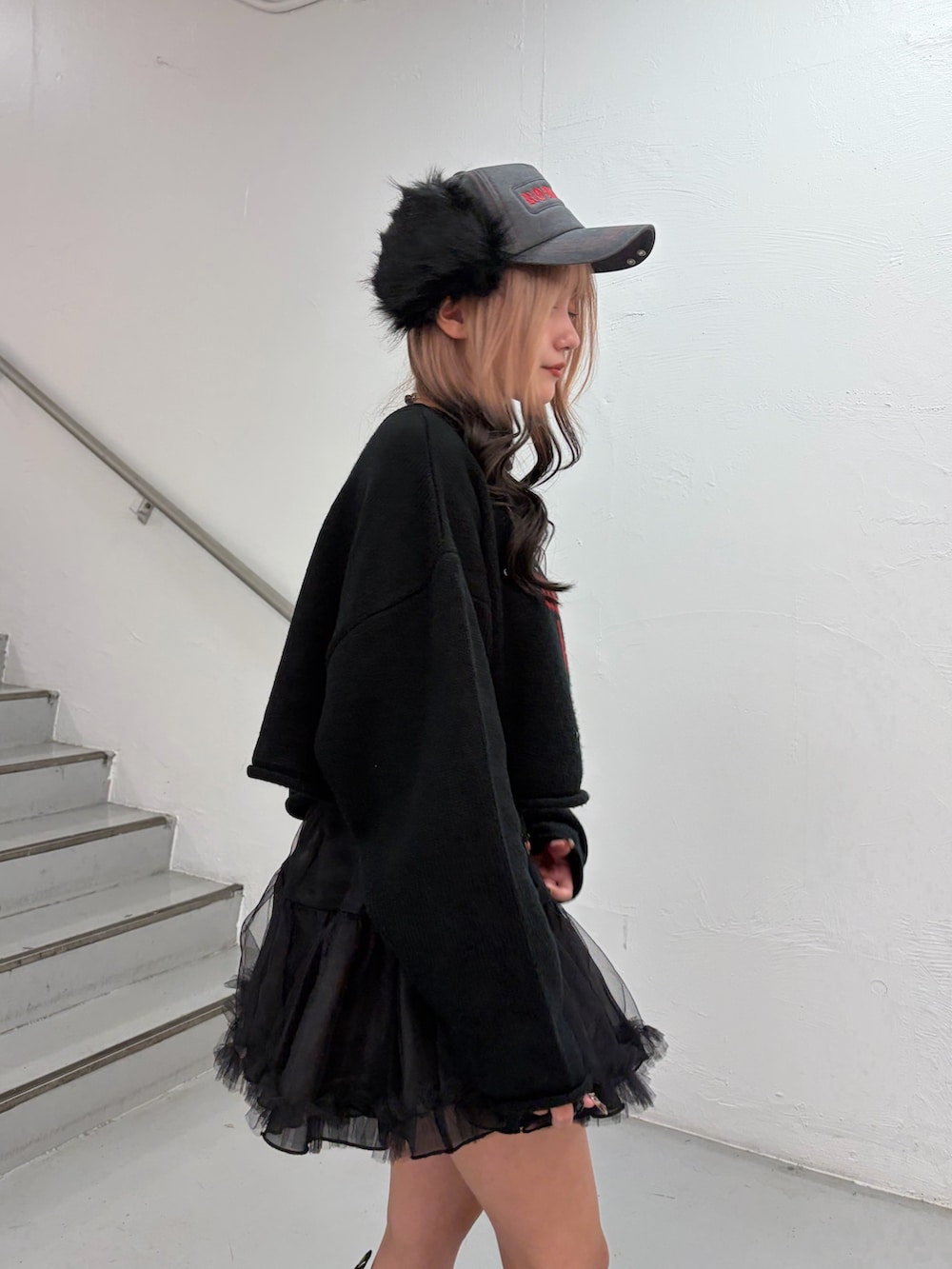 ブラック系のニット/セーター、ブラック系のスカート、ブラック系のキャップを着用したレディースの秋コーディネートの6枚目の写真