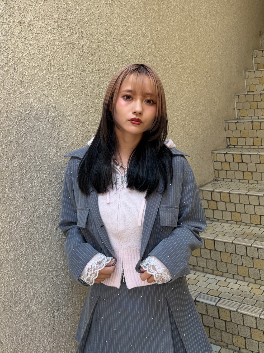 グレー系のテーラードジャケット、グレー系のスカート、ピンク系のパーカーを着用したレディースの冬コーディネートの4枚目の写真