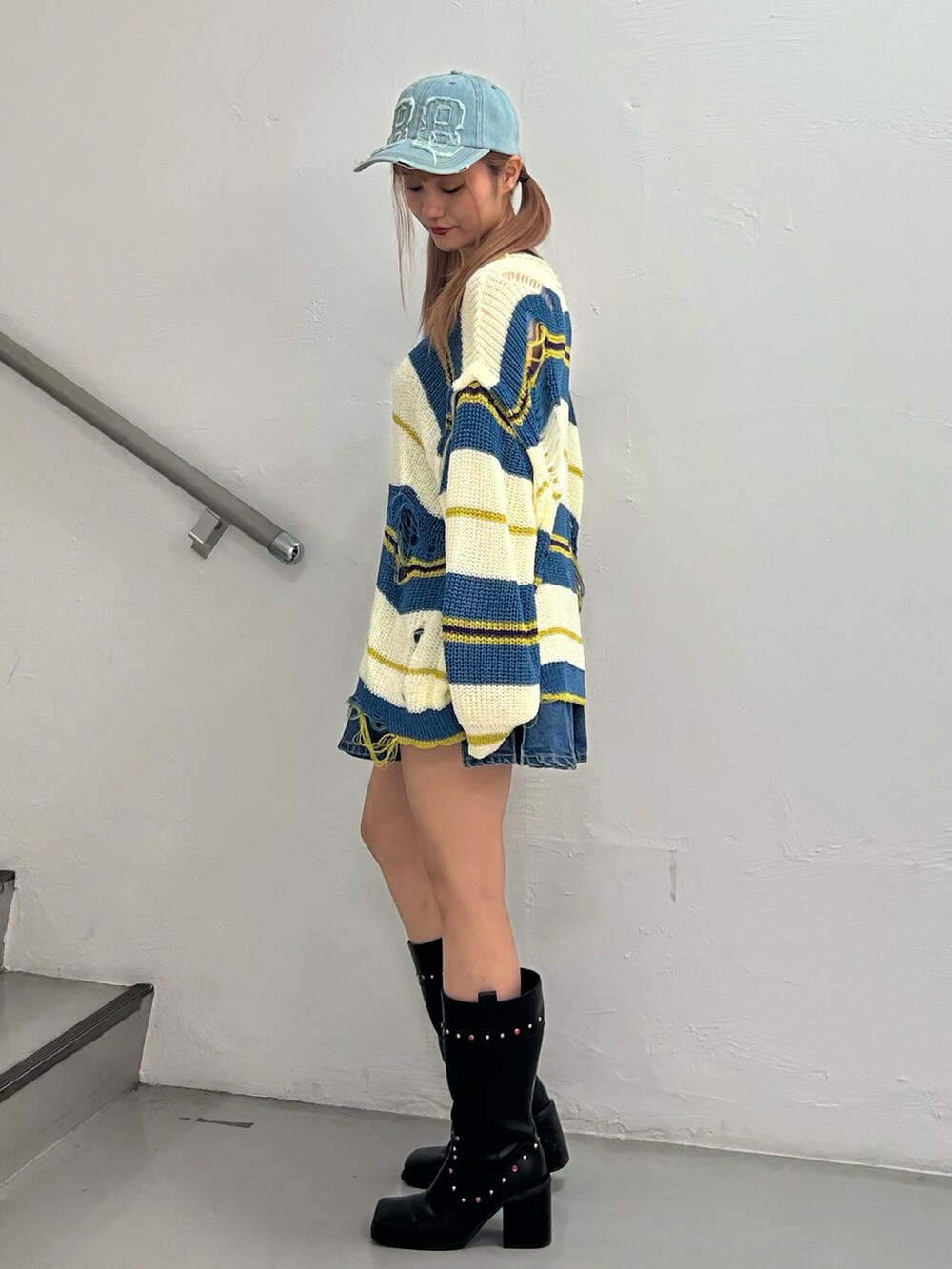 ホワイト系のニット/セーター、ブルー系のデニムスカート、ブラック系のブーツを着用したレディースの春コーディネートの2枚目の写真