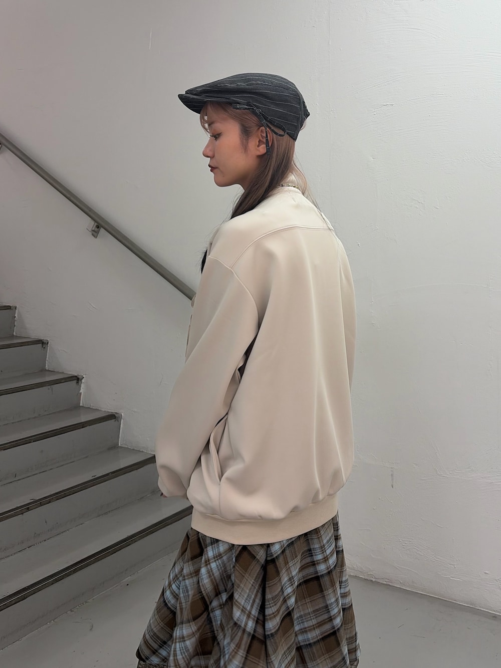 ホワイト系のジャージ、ブラウン系のスカート、グレー系のハンチング/ベレー帽を着用したレディースの冬コーディネートの6枚目の写真