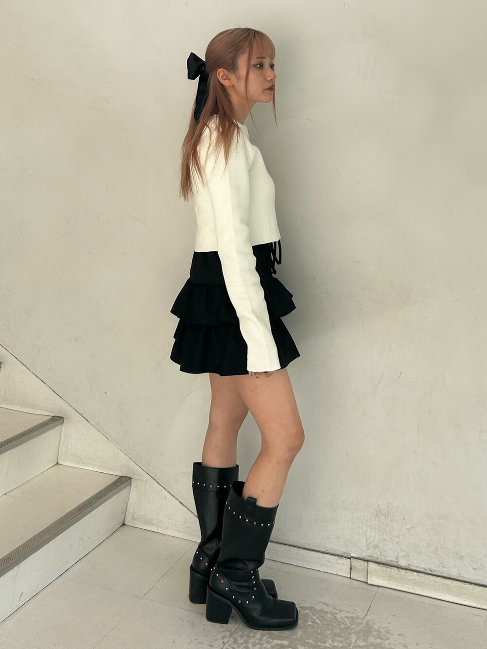 ホワイト系のカーディガン/ボレロ、ブラック系のスカート、ブラック系のブーツを着用したレディースの春コーディネートの2枚目の写真