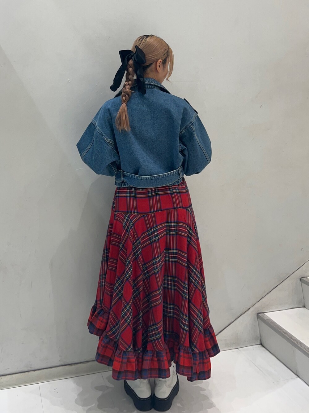レッド系のスカート、ブラック系のTシャツ/カットソー、ブルー系のライダースジャケットを着用したレディースの秋コーディネートの3枚目の写真