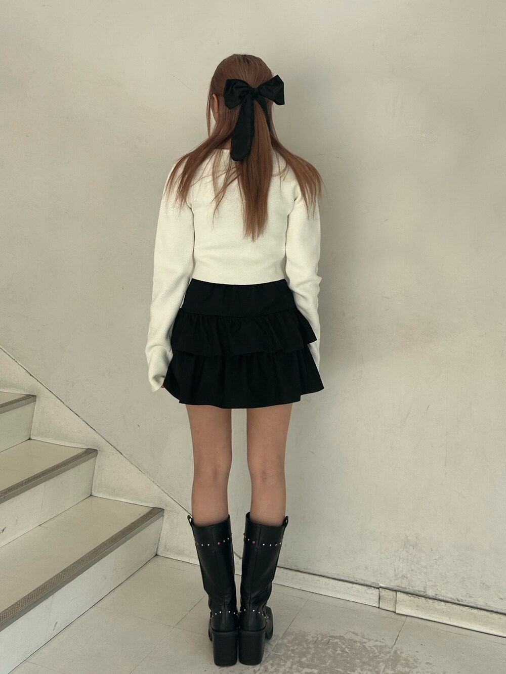 ホワイト系のカーディガン/ボレロ、ブラック系のスカート、ブラック系のブーツを着用したレディースの春コーディネートの3枚目の写真