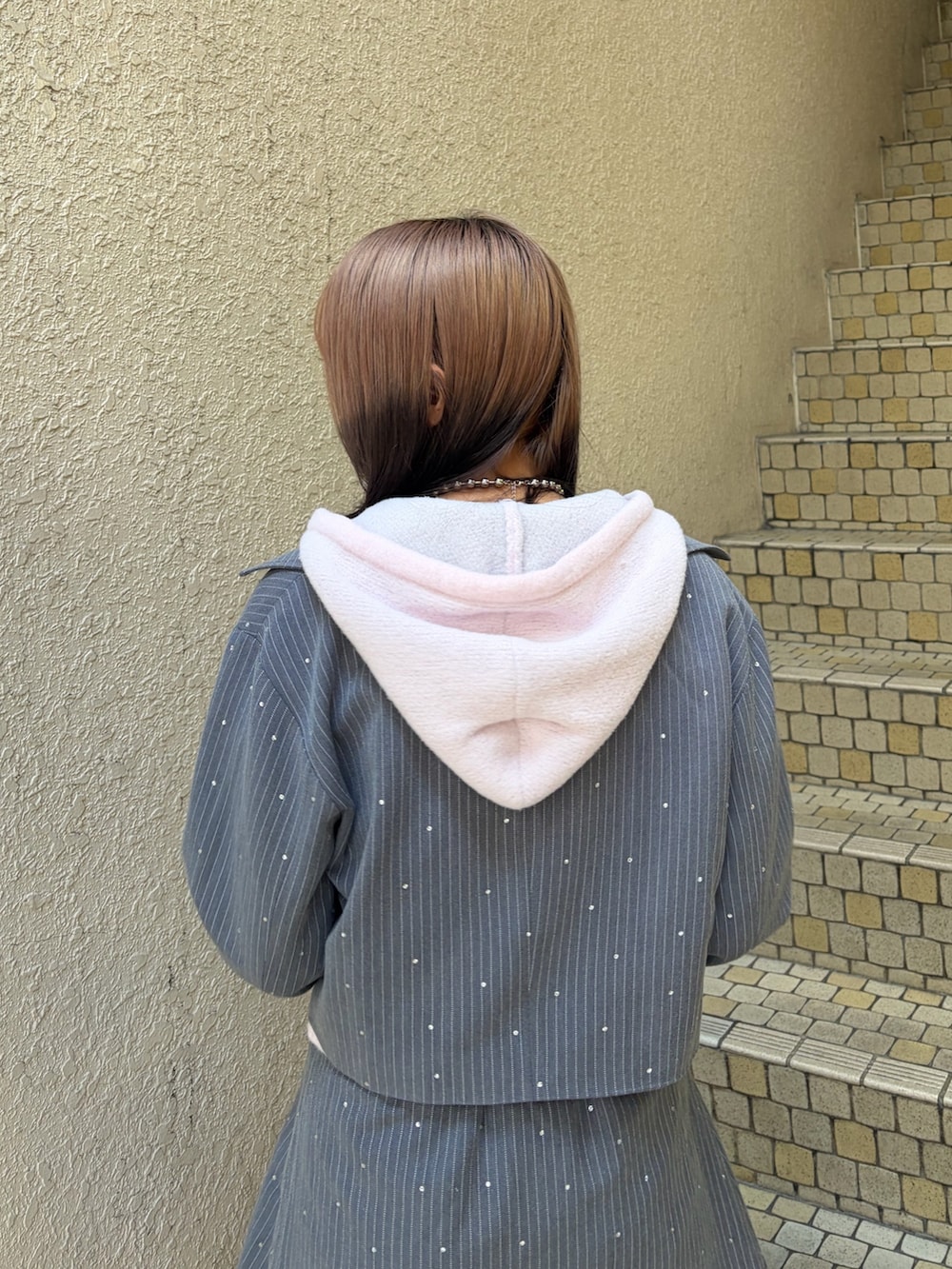 グレー系のテーラードジャケット、グレー系のスカート、ピンク系のパーカーを着用したレディースの冬コーディネートの6枚目の写真