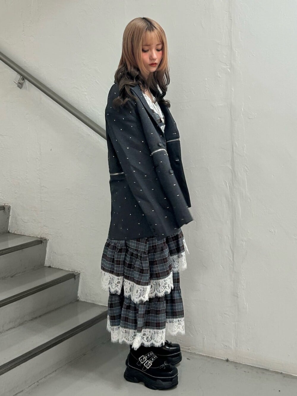 グレー系のテーラードジャケット、ブラック系のスニーカー、ブラウン系のワンピースを着用したレディースの秋コーディネートの2枚目の写真