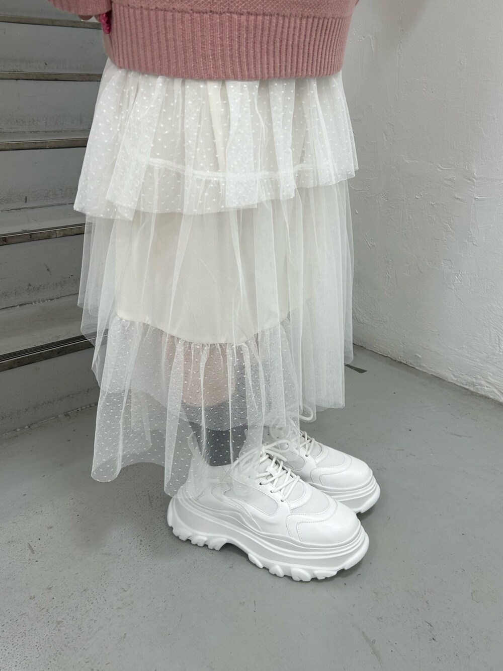 ピンク系のニット/セーター、ホワイト系のシャツ/ブラウス、ホワイト系のスカートを着用したレディースの冬コーディネートの9枚目の写真