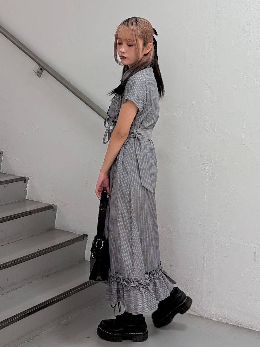 グレー系のワンピース、ブラック系のハンドバッグを着用したレディースの春コーディネートの3枚目の写真