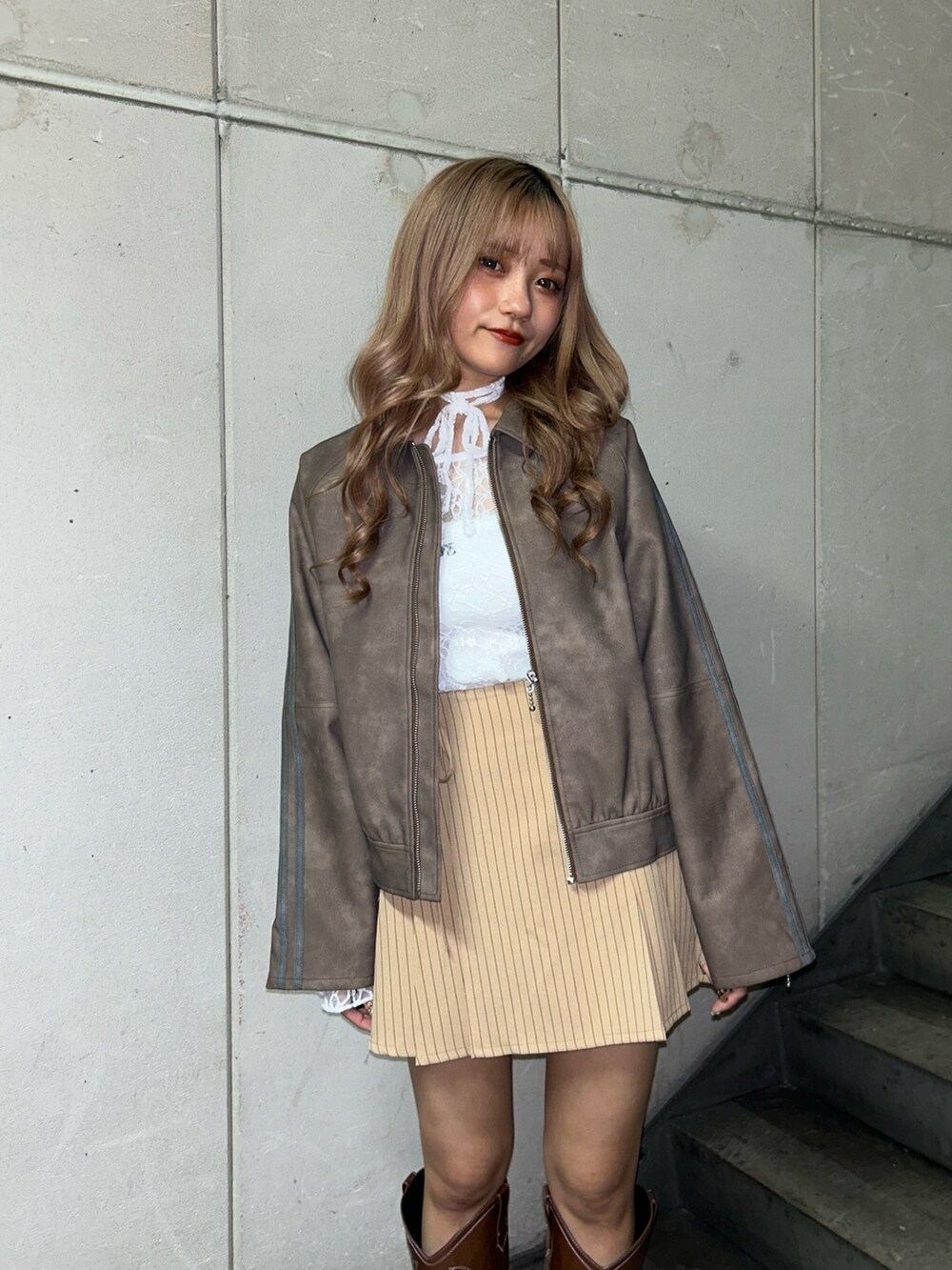 ブラウン系のブルゾン、ホワイト系のTシャツ/カットソー、ベージュ系のスカートを着用したレディースの冬コーディネートの4枚目の写真