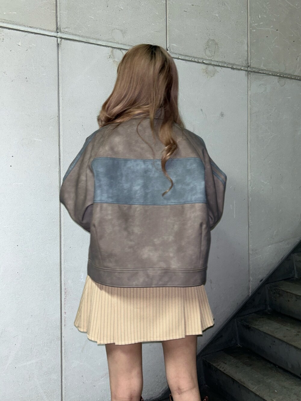 ブラウン系のブルゾン、ホワイト系のTシャツ/カットソー、ベージュ系のスカートを着用したレディースの冬コーディネートの6枚目の写真