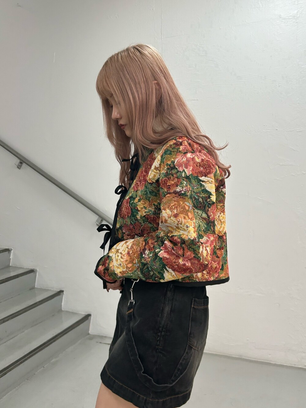 ブラック系のノーカラージャケット、ホワイト系のニット/セーター、ブラック系のデニムスカートを着用したレディースの冬コーディネートの5枚目の写真