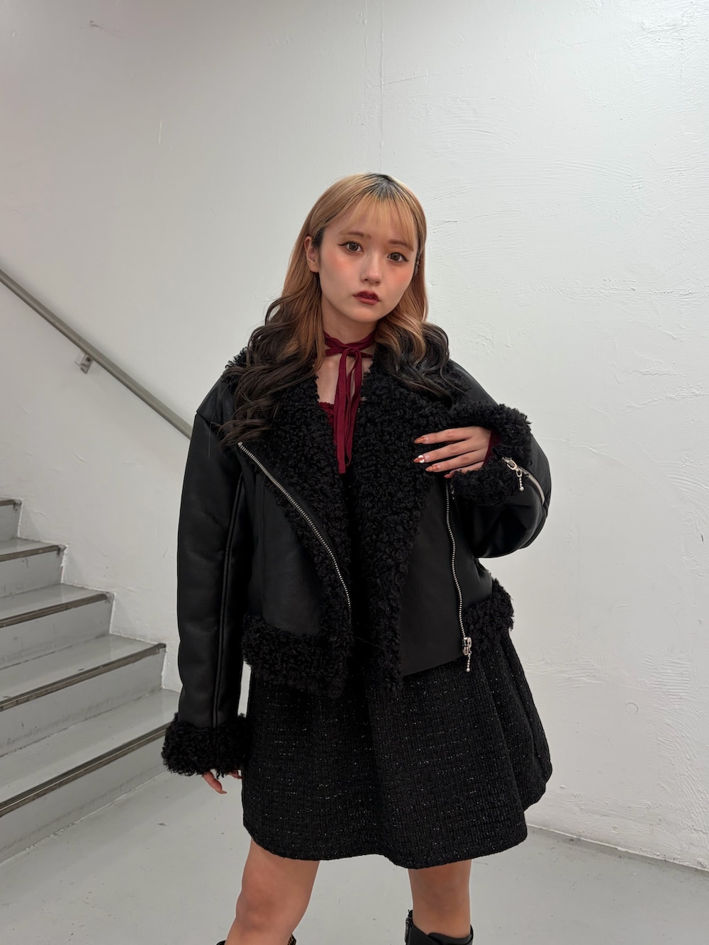 ブラック系のムートンコート、ブラック系のワンピース、レッド系のニット/セーターを着用したレディースの秋コーディネートの5枚目の写真