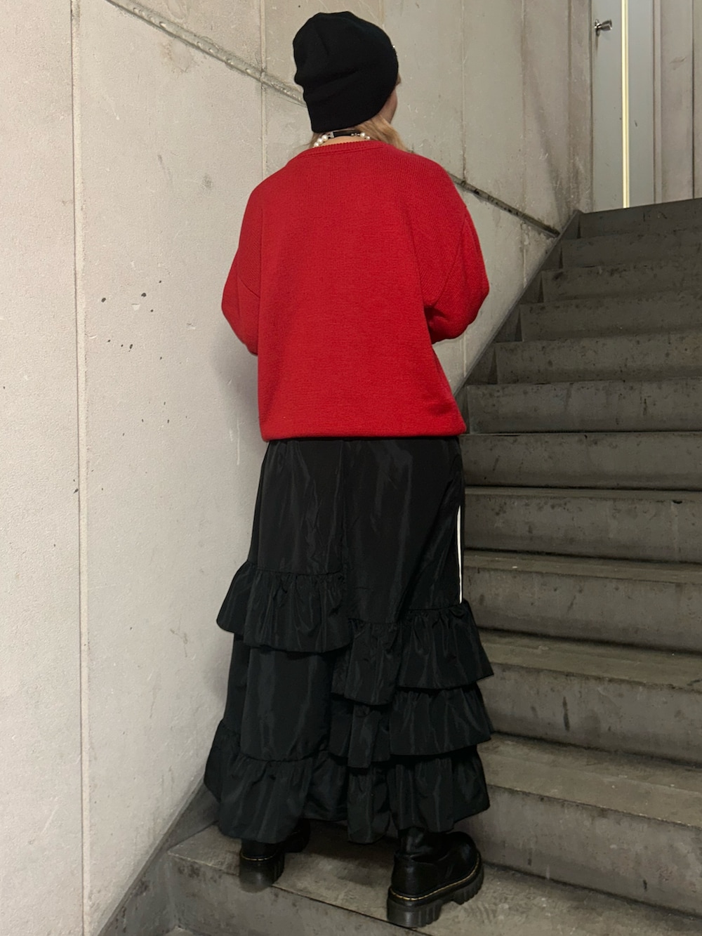 レッド系のニット/セーター、ブラック系のスカート、ブラック系のチョーカーを着用したレディースの秋コーディネートの3枚目の写真