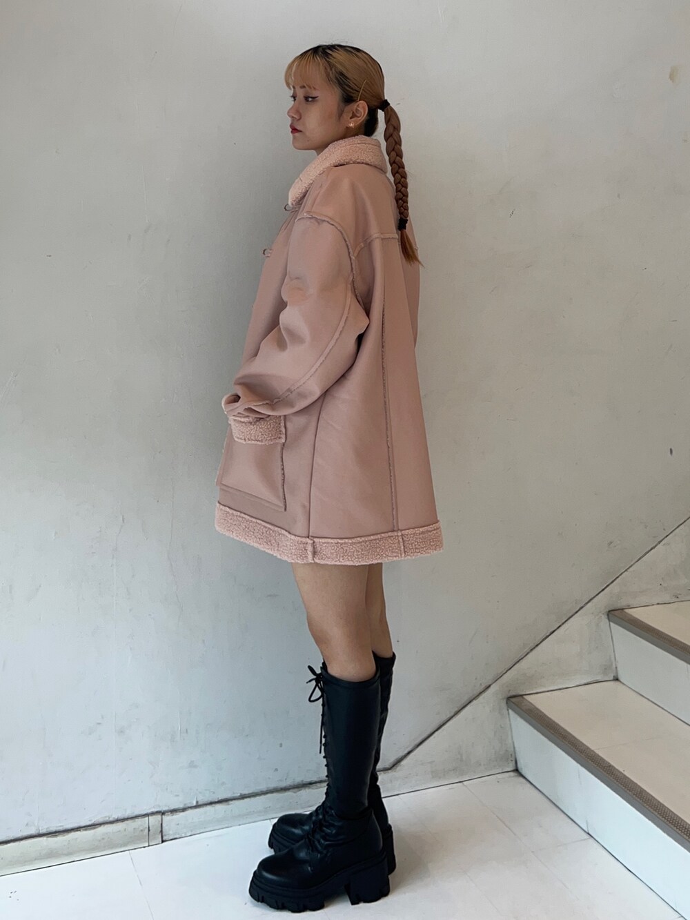 ピンク系のムートンコート、ホワイト系のスウェット、ブラック系のブーツを着用したレディースの秋コーディネートの2枚目の写真