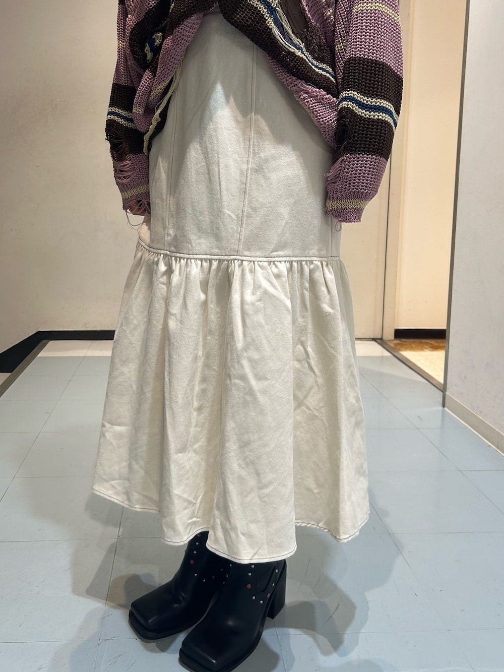 ピンク系のニット/セーター、ホワイト系のワンピース、ブラック系のブーツを着用したレディースの春コーディネートの8枚目の写真