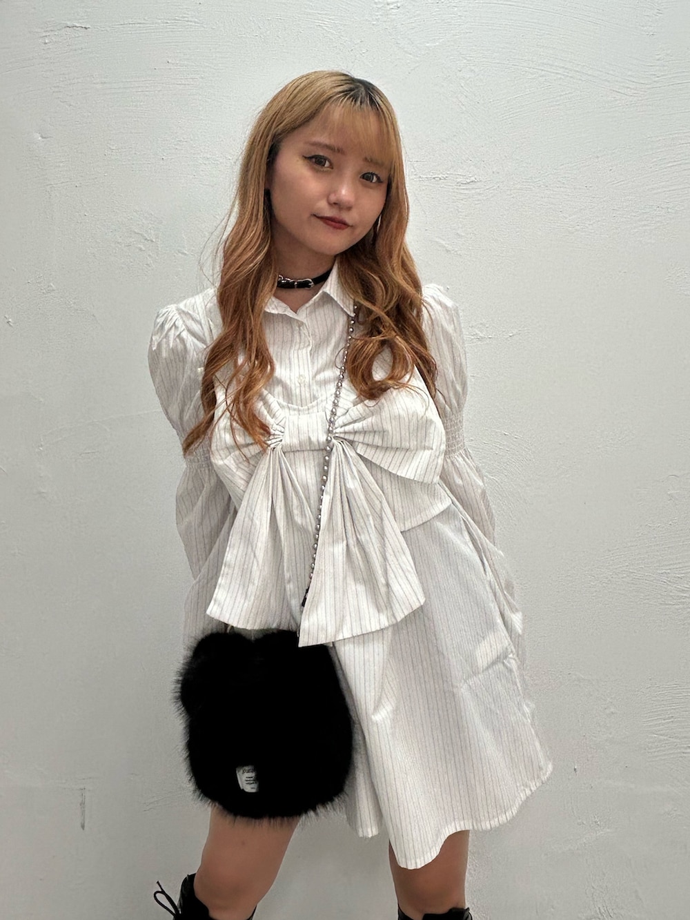 ホワイト系のシャツワンピース、ブラック系のハンドバッグ、ブラック系のブーツを着用したレディースの夏コーディネートの4枚目の写真