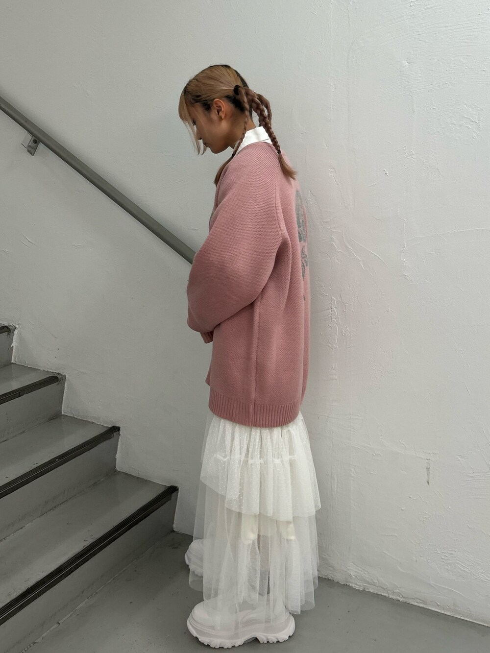 ピンク系のニット/セーター、ホワイト系のシャツ/ブラウス、ホワイト系のスカートを着用したレディースの冬コーディネートの2枚目の写真