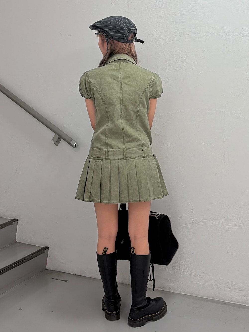 グリーン系のワンピース、ブラック系のボストンバッグ、グレー系のハンチング/ベレー帽を着用したレディースの冬コーディネートの2枚目の写真