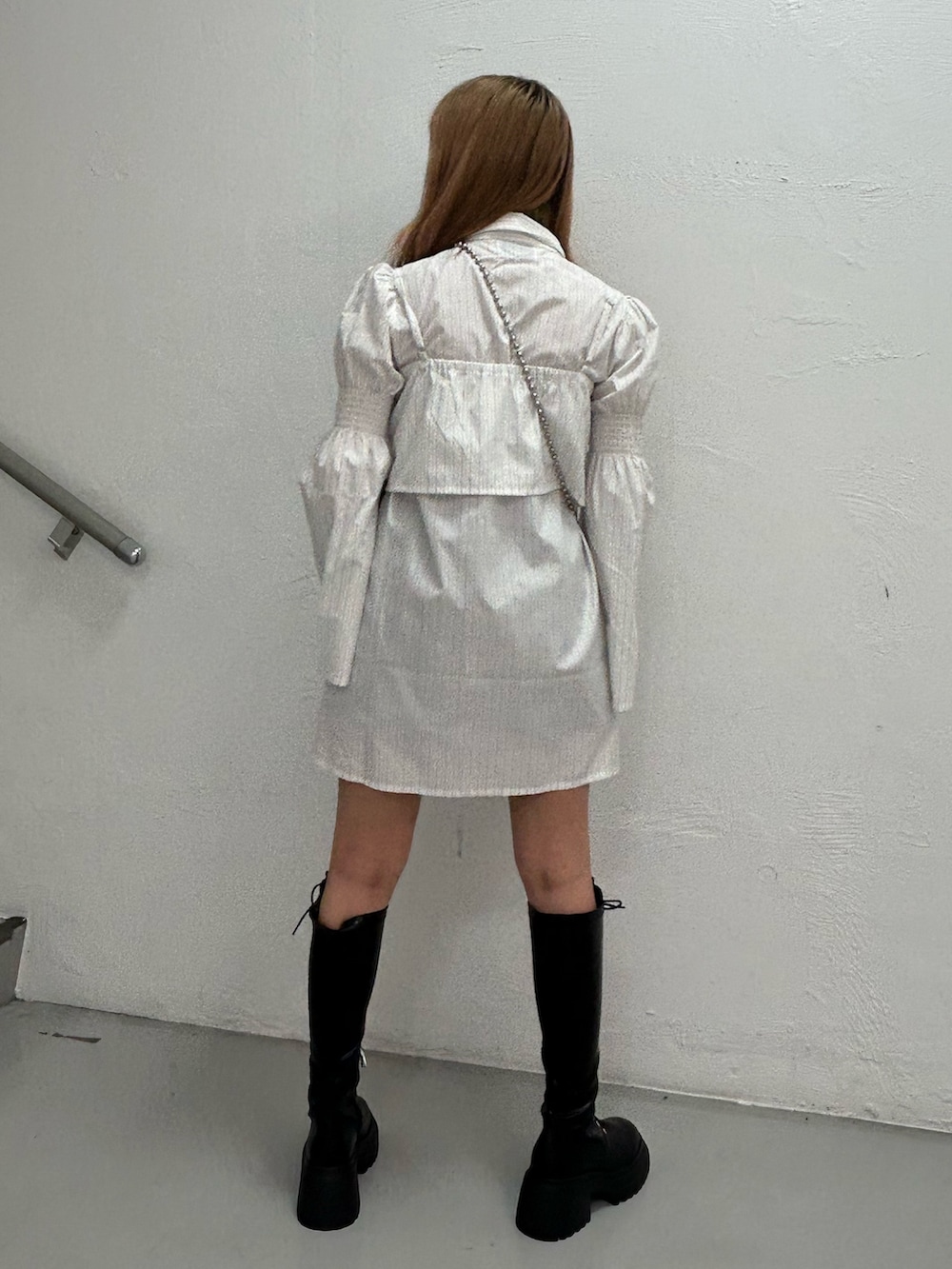 ホワイト系のシャツワンピース、ブラック系のハンドバッグ、ブラック系のブーツを着用したレディースの夏コーディネートの3枚目の写真