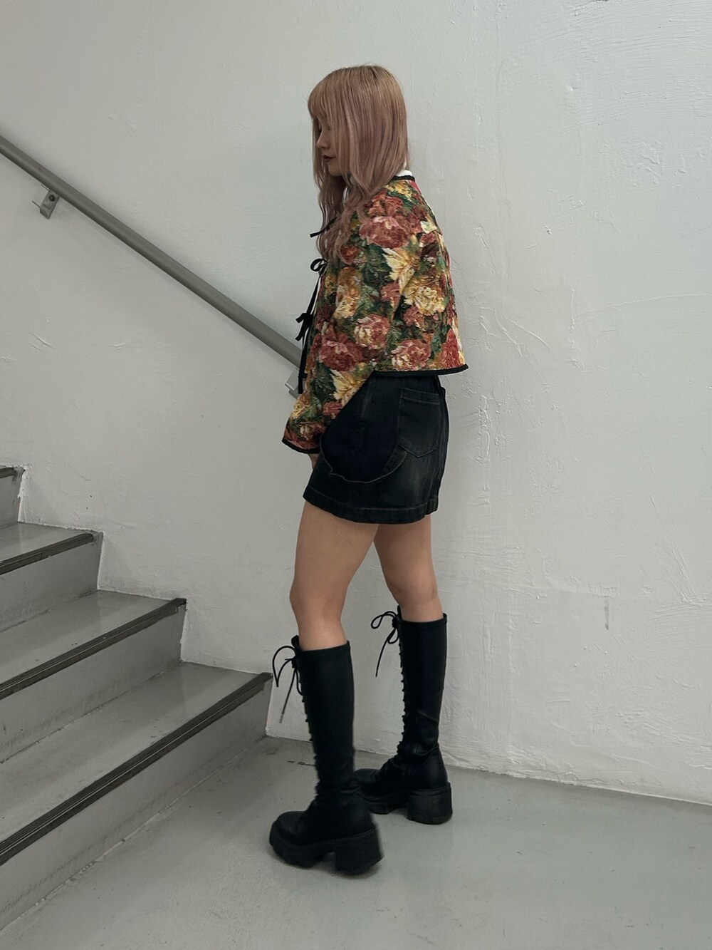 ブラック系のノーカラージャケット、ホワイト系のニット/セーター、ブラック系のデニムスカートを着用したレディースの冬コーディネートの2枚目の写真