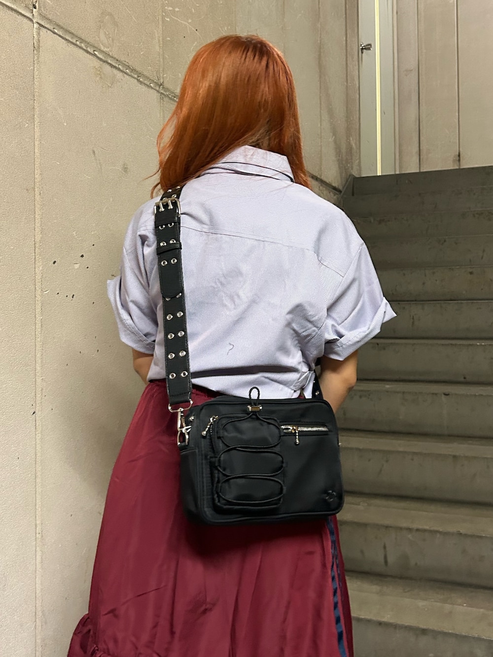 パープル系のシャツ/ブラウス、レッド系のスカート、ブラック系のショルダーバッグを着用したレディースの夏コーディネートの6枚目の写真