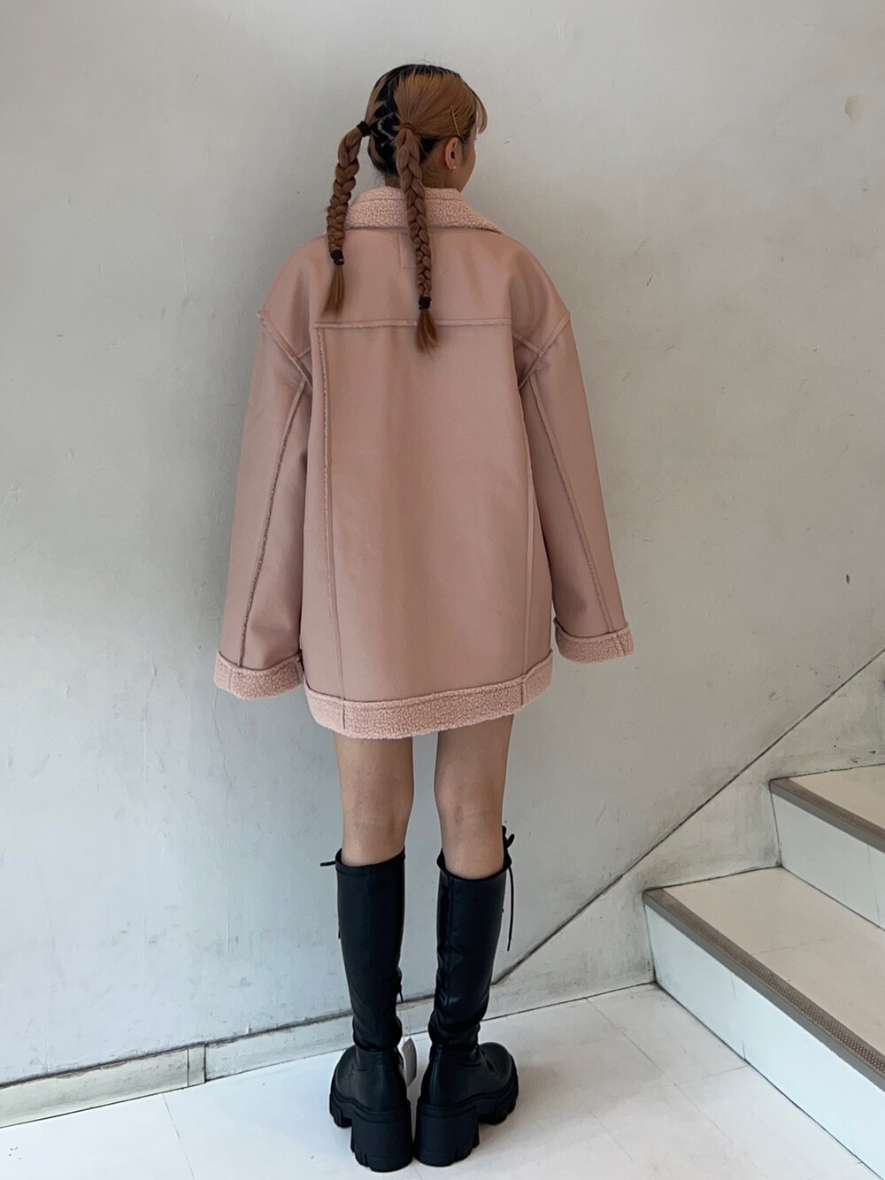 ピンク系のムートンコート、ホワイト系のスウェット、ブラック系のブーツを着用したレディースの秋コーディネートの3枚目の写真